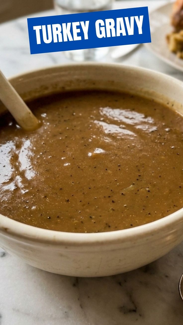 A rich, dark brown turkey gravy in a white ceramic gravy boat.